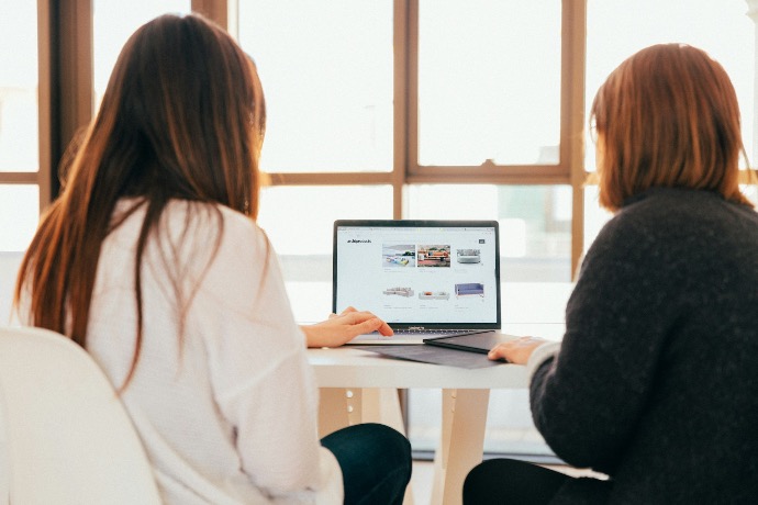 two women talking about Twelve2 Marketing while looking at laptop computer